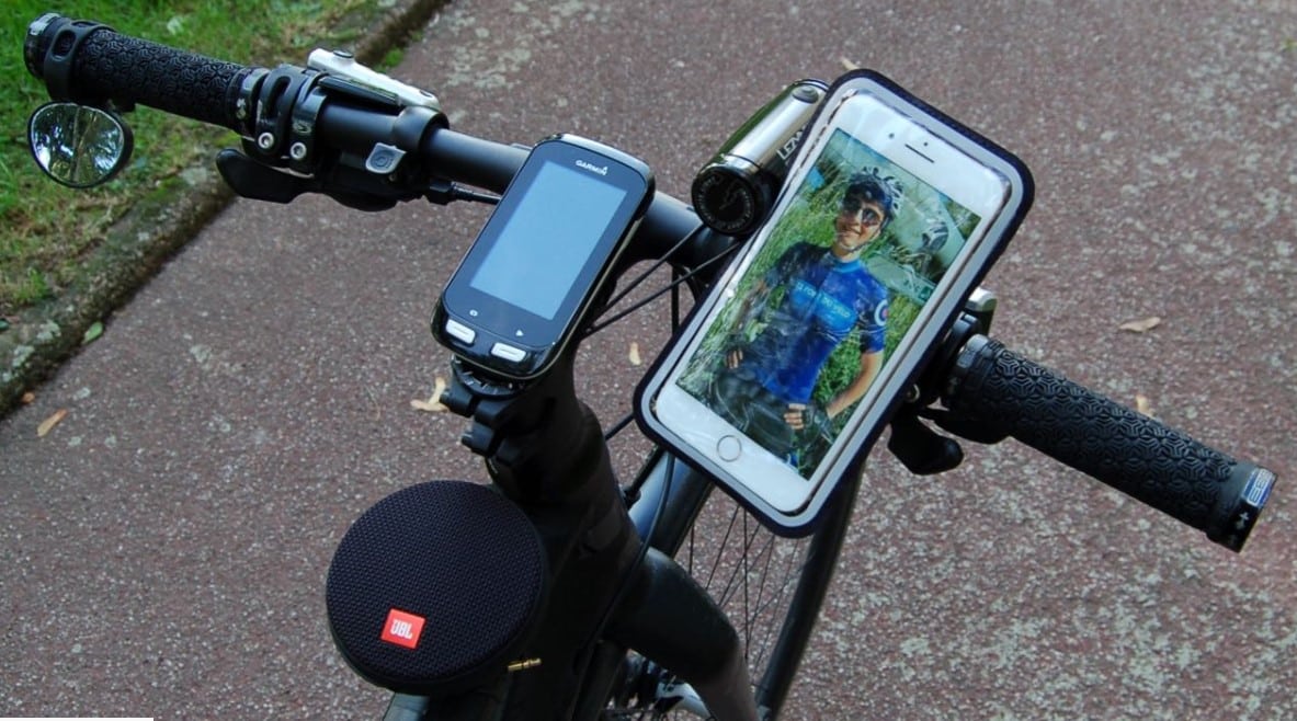 Un smartphone fixé sur un vélo à côté d'un compteur GPS.